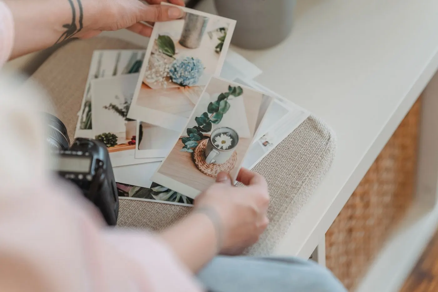 Des tirages photo étalés sur une table, triés à la main à côté d’un appareil photo
